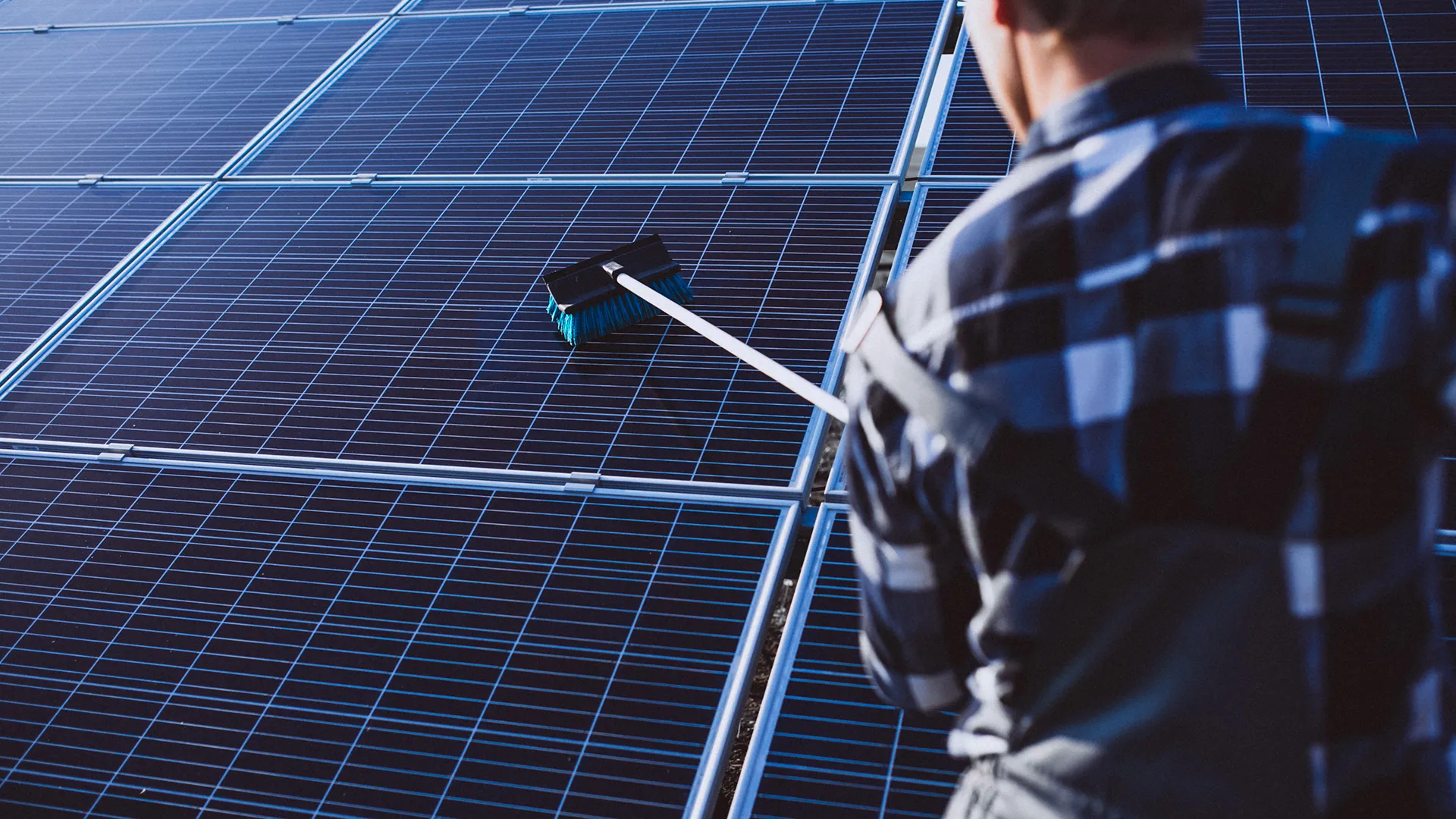 Technicien Léon nettoyant des panneaux photovoltaïques vu de dos dans l'est de la France